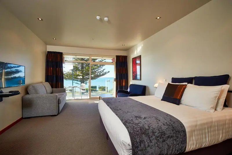 Une chambre lumineuse avec un grand lit et un coin salon donnant sur une vue mer.