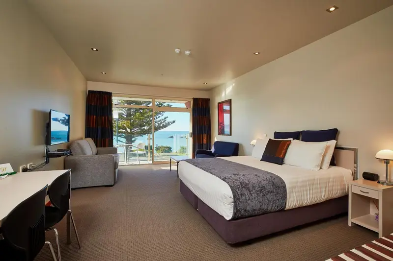 Une chambre spacieuse avec un lit et un coin salon donnant sur l'océan.