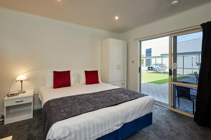 Une chambre lumineuse avec un lit double et un accès à une terrasse.
