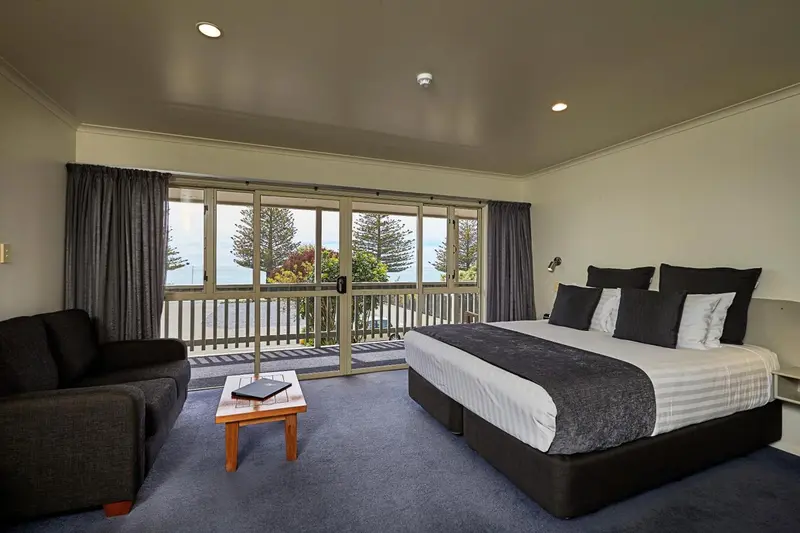 Une chambre spacieuse avec un grand lit et un coin salon donnant sur une vue extérieure.