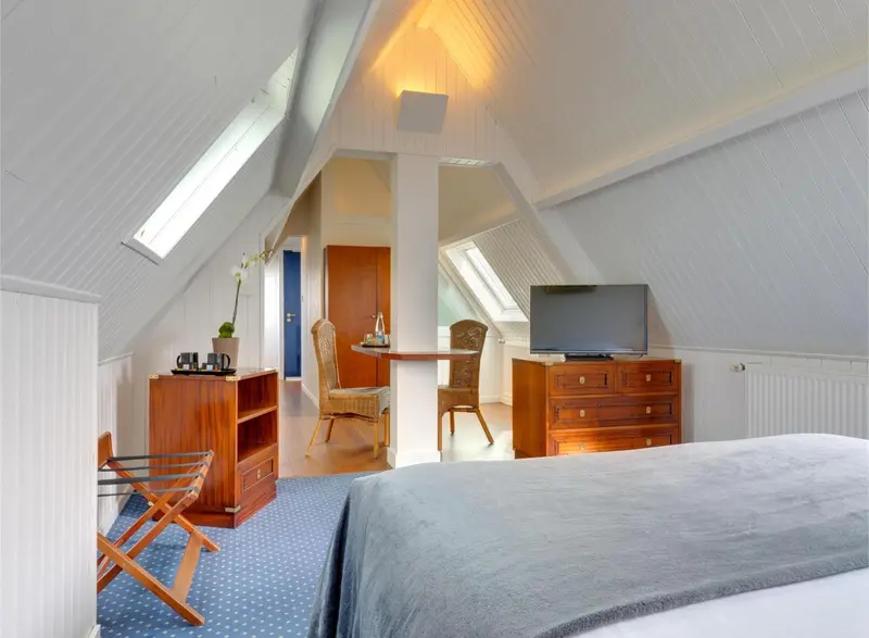 Une chambre mansardée lumineuse avec un lit et un coin repas.