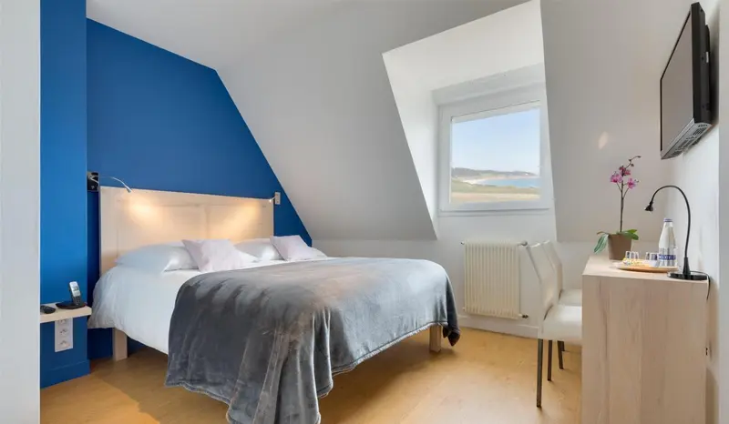 Une chambre lumineuse avec un lit double et une vue sur la mer.