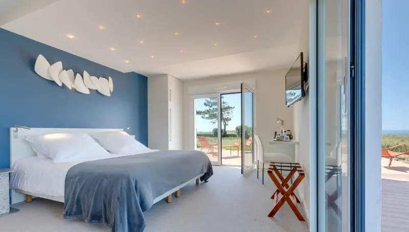 Une chambre lumineuse avec un grand lit et une vue sur l'extérieur.