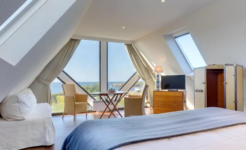 Une chambre mansardée lumineuse avec vue sur la mer.
