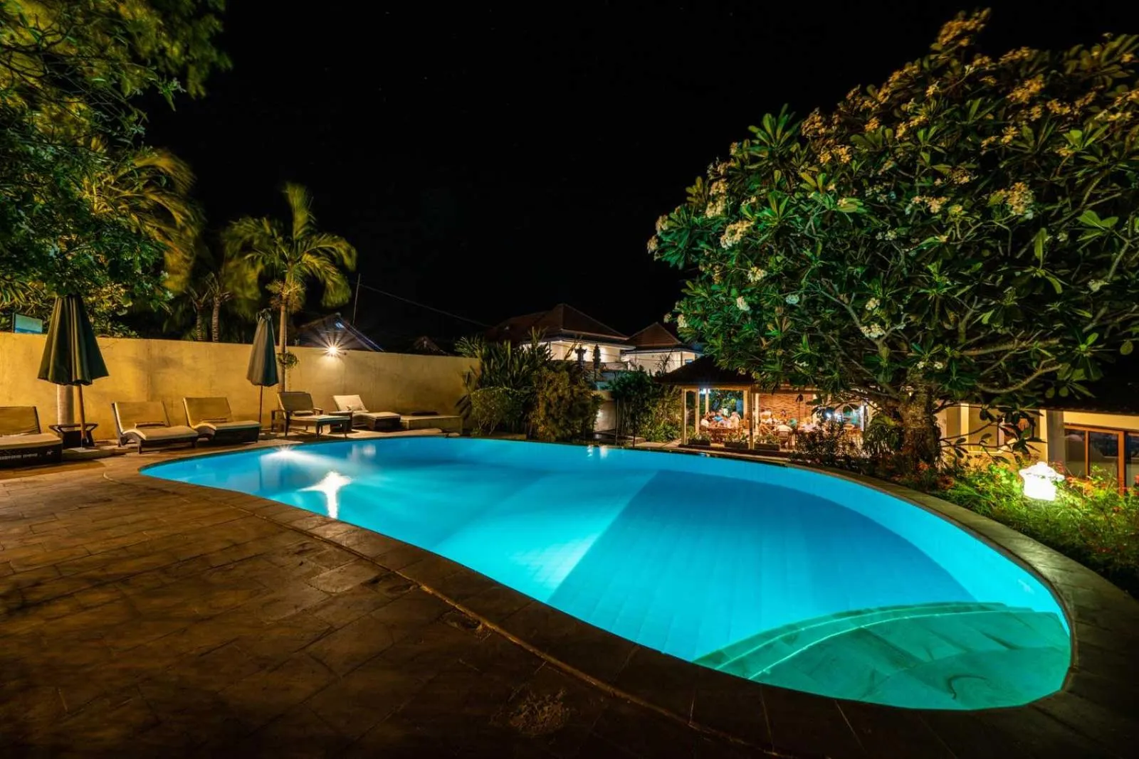 Piscine illuminée au crépuscule avec mobilier de détente.