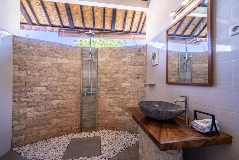 Une douche à l'extérieur avec un sol en galets et un lavabo en pierre.