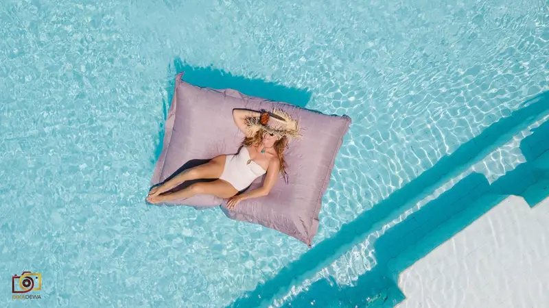 Une femme se relaxe sur un coussin flottant dans une piscine ensoleillée.