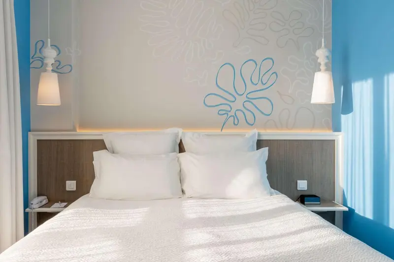 Un lit double avec oreillers blancs dans une chambre lumineuse.
