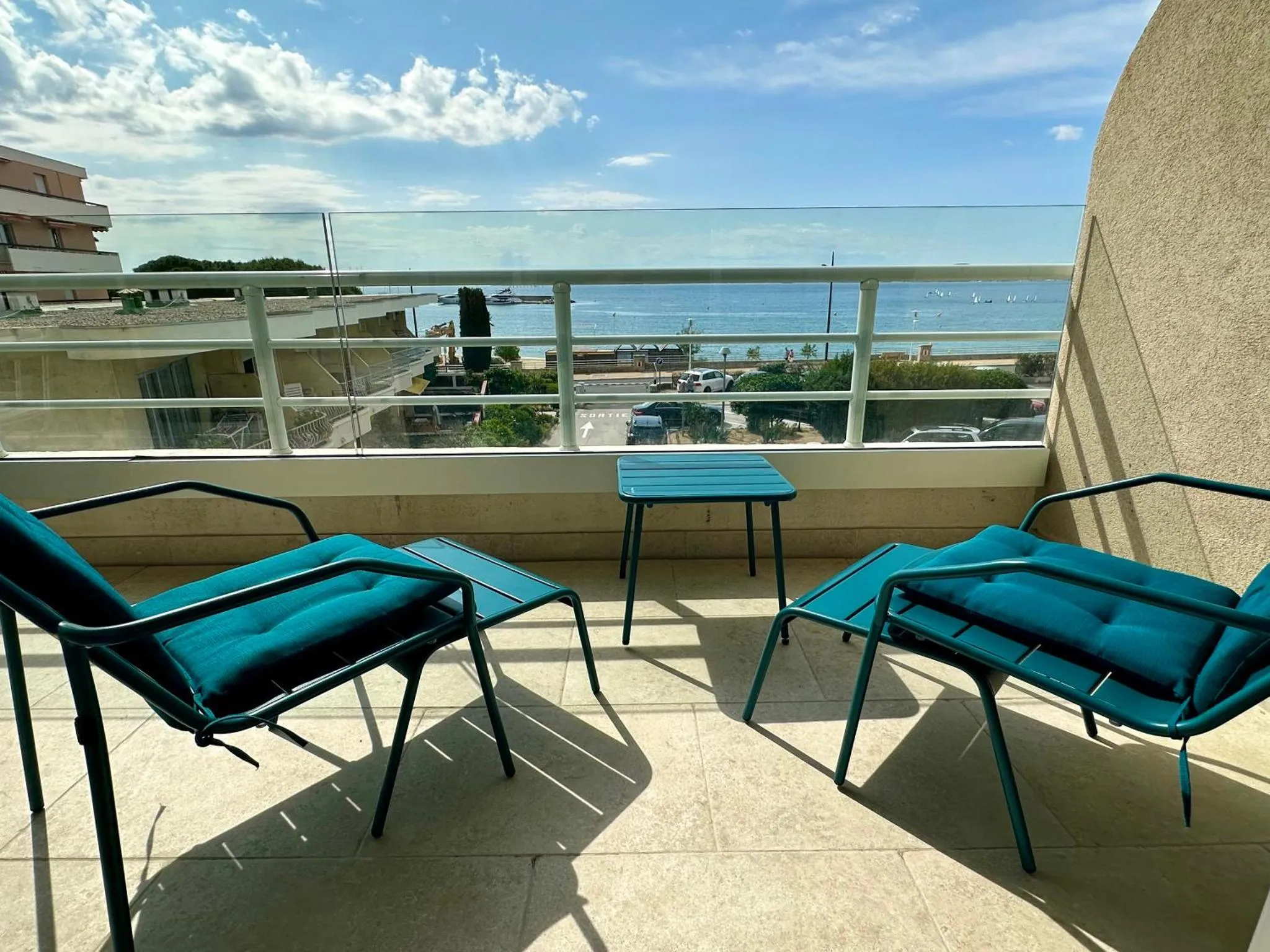 Deux chaises longues turquoise sur une terrasse ensoleillée avec vue sur la mer.