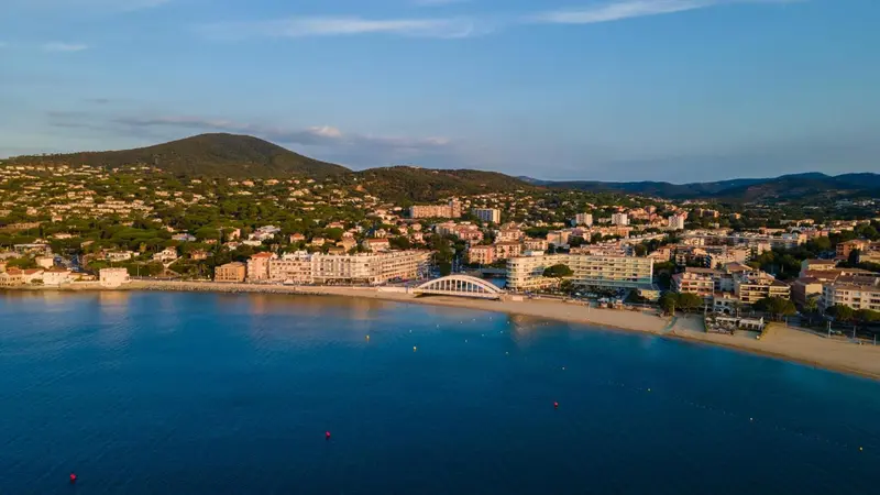 Vue aérienne d'une station balnéaire avec une plage et une colline en arrière-plan.