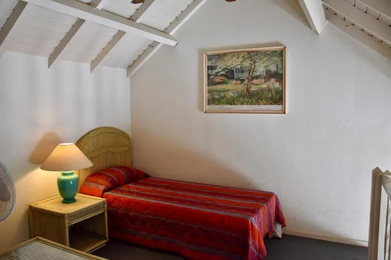 Une chambre avec un lit simple et une lampe de chevet.