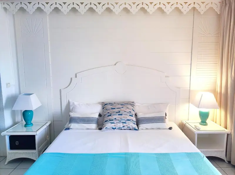 Une chambre lumineuse avec un grand lit recouvert d'une courtepointe bleue.