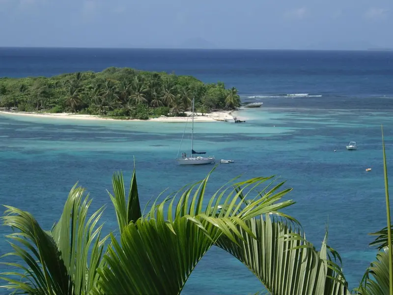 Vue aérienne d'une île tropicale avec des bateaux amarrés dans une baie turquoise.
