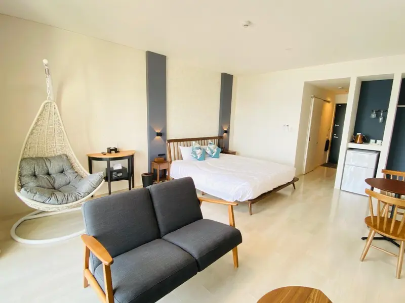 Espace de vie intérieur lumineux avec canapé, lit et fauteuil suspendu.