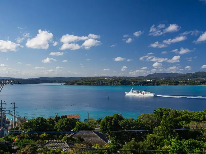 Vue panoramique sur une baie turquoise et un bateau en mer.