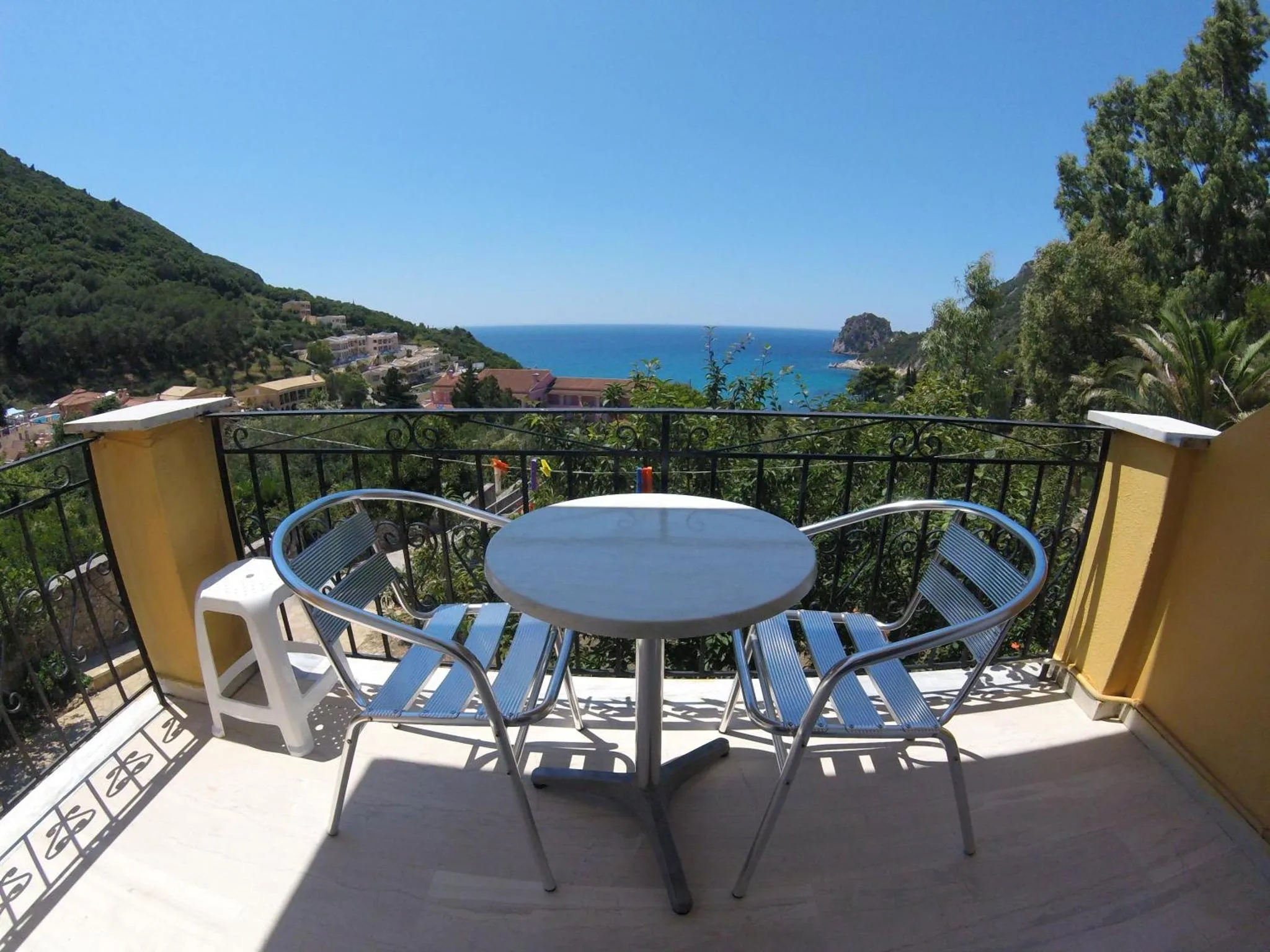 Terrasse avec table et chaises donnant sur la mer et les collines.