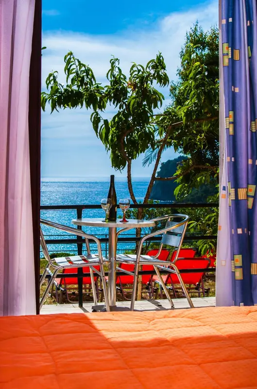 Une table et des chaises se trouvent sur un balcon avec vue sur la mer.