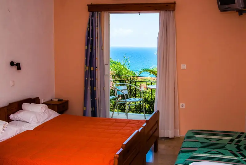 Une chambre lumineuse donne sur une vue mer depuis un balcon.