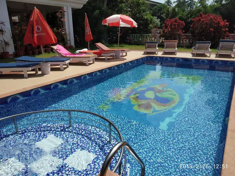 Transats bleus alignés au bord d'une piscine carrelée.