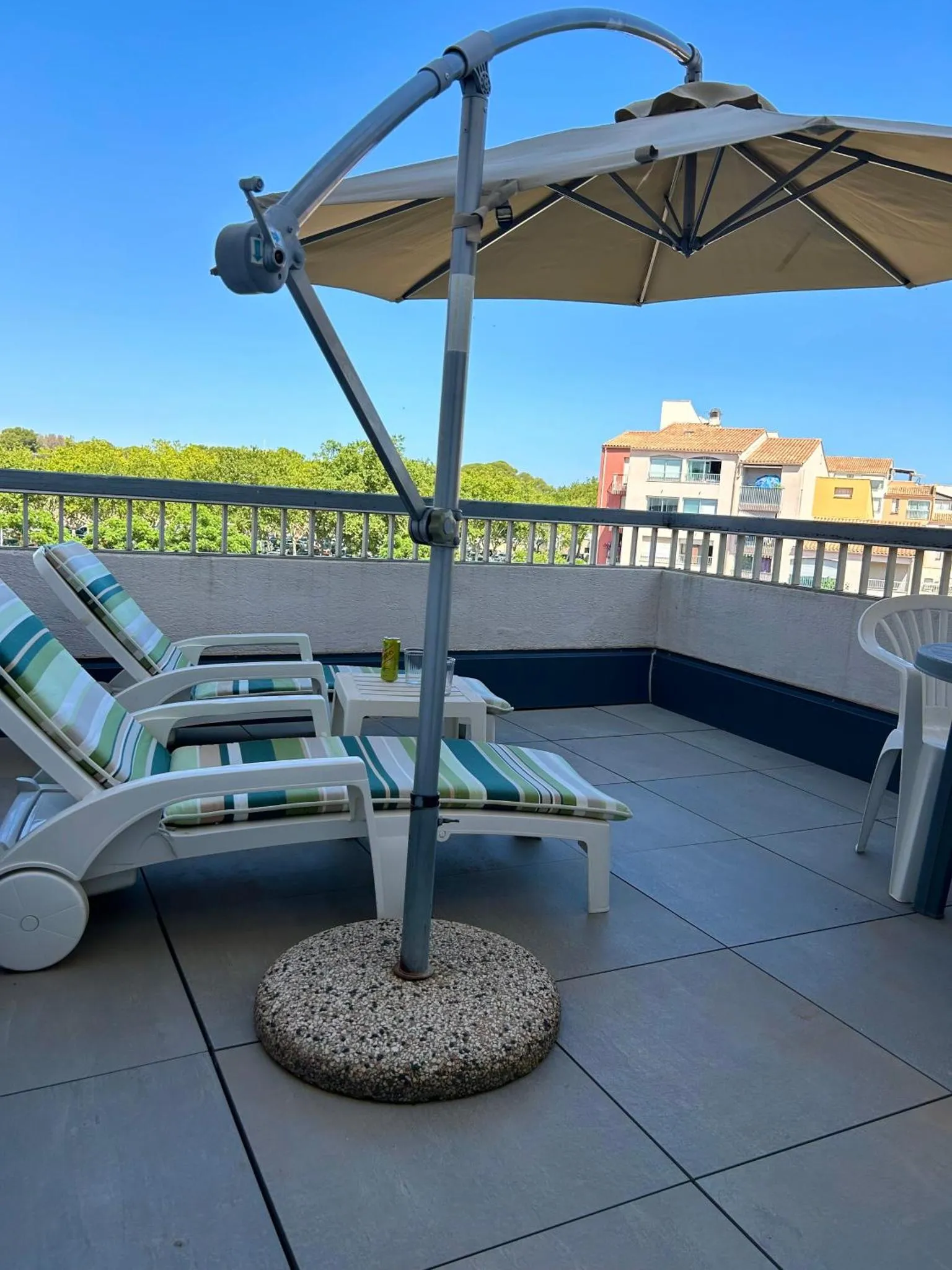 Terrasse aménagée avec des transats et un parasol.