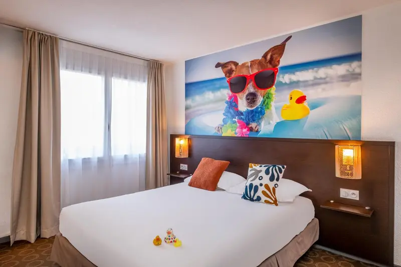 Une chambre lumineuse avec un grand lit et une décoration murale colorée.