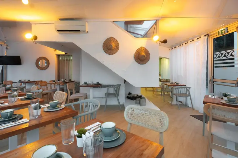 Une salle lumineuse avec des tables dressées pour le repas.