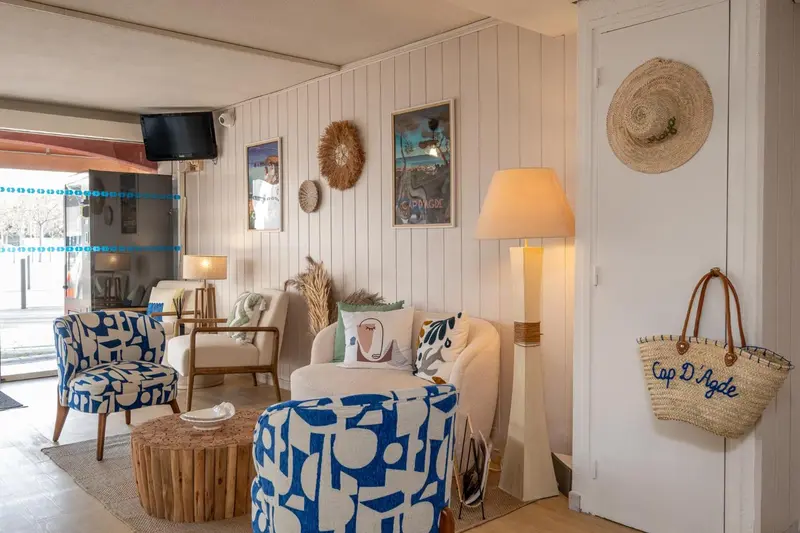 Un salon clair avec des fauteuils confortables et des décorations murales.