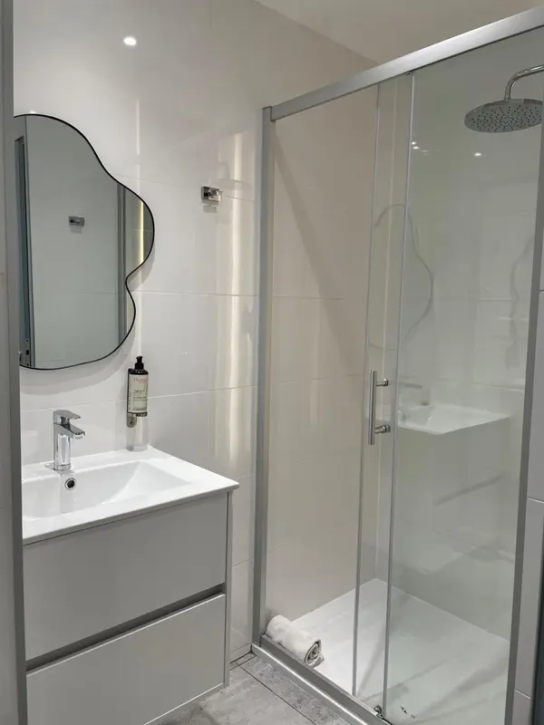 Une salle de bain moderne avec douche à l'italienne et grand miroir.