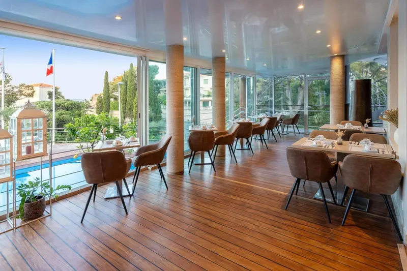 Une salle lumineuse avec des tables et des chaises, donnant sur une vue extérieure.