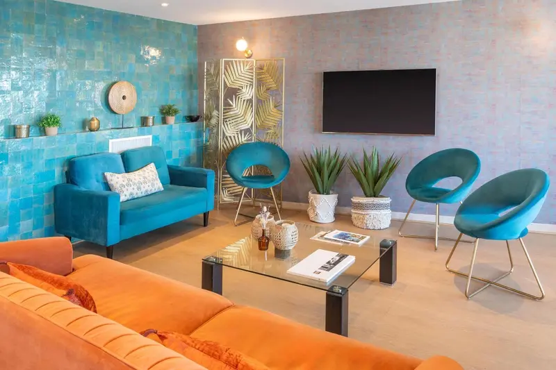 Un salon moderne avec canapés colorés et une télévision murale.