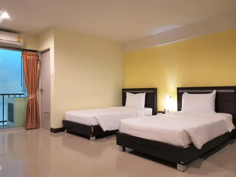 Chambre lumineuse avec deux lits simples et une baie vitrée.
