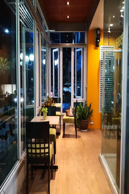 Une salle lumineuse avec des tables et des chaises près de grandes fenêtres.