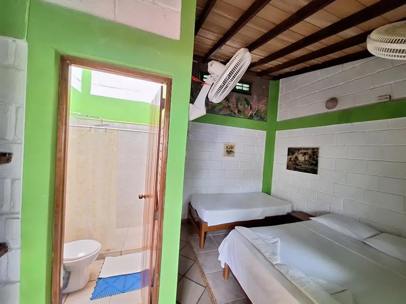Une chambre lumineuse avec deux lits simples et une salle de bain attenante.