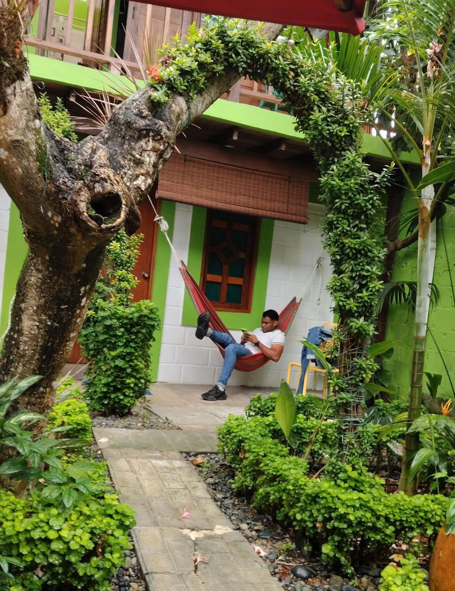 Un homme se détend dans un hamac devant un bâtiment vert.