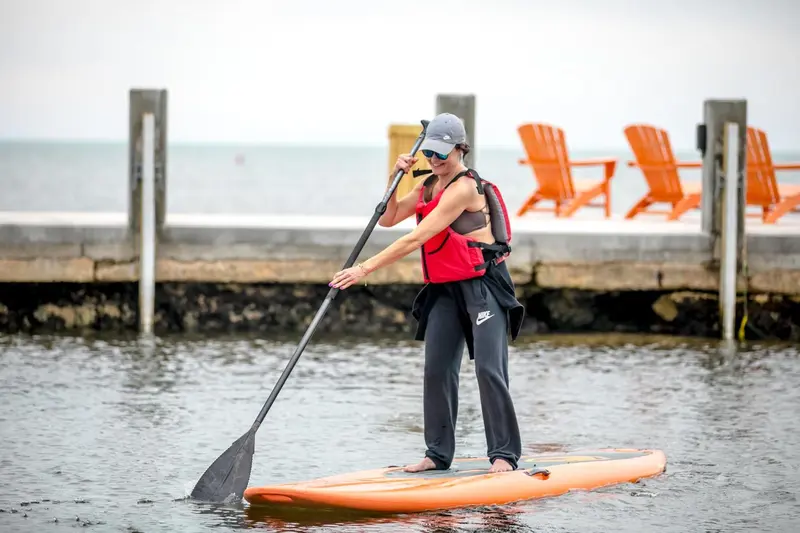 Une personne se tient debout sur une planche de surf, pagayant en mer.
