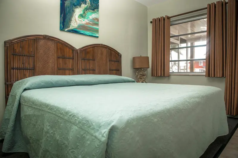 Une chambre lumineuse avec un grand lit recouvert d'une courtepointe turquoise.