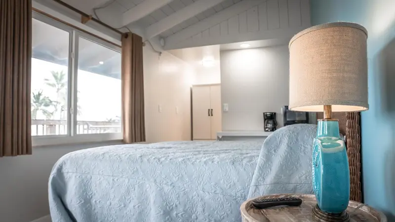 Une chambre lumineuse avec un lit recouvert d'une courtepointe et une vue sur la végétation.