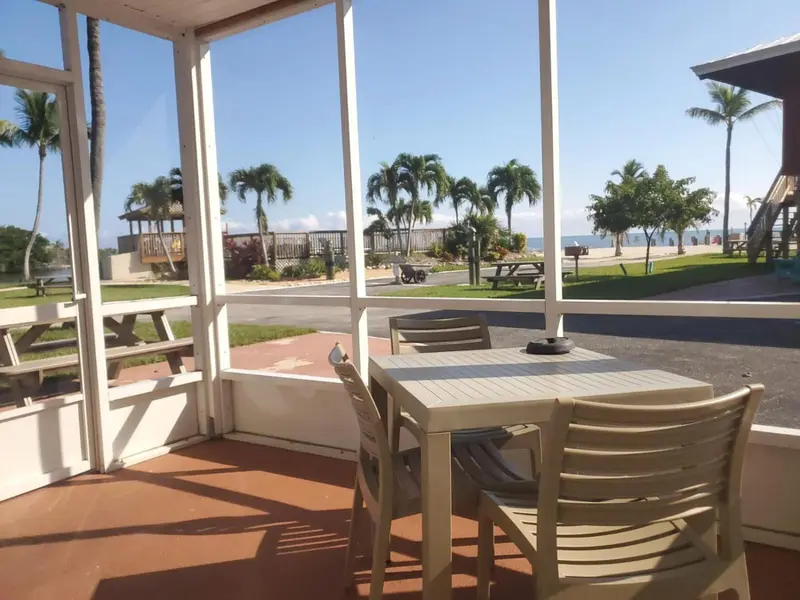 Une table et des chaises se trouvent sur une terrasse ombragée avec vue sur la plage et la mer.