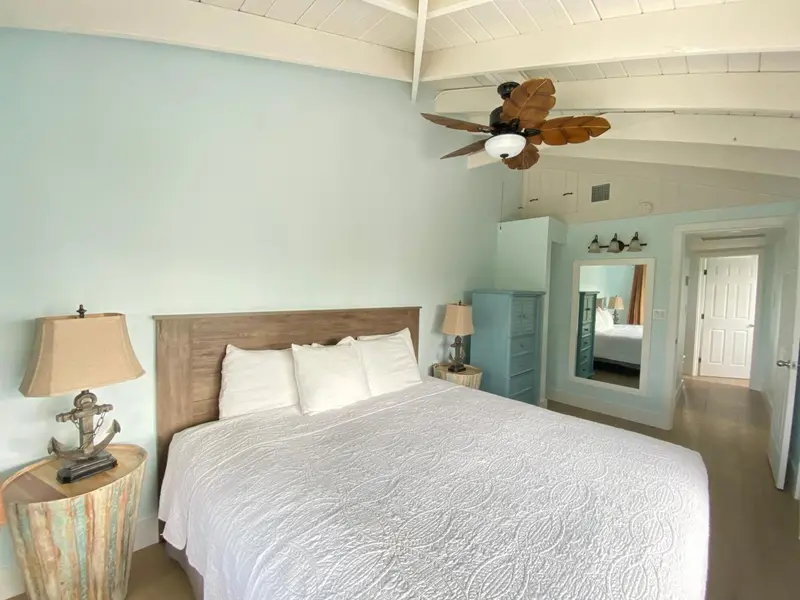 Une chambre lumineuse avec un grand lit recouvert d'une courtepointe blanche.