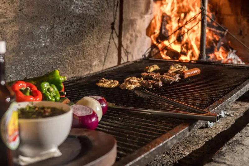 Viande et légumes grillés sur un barbecue en pierre.
