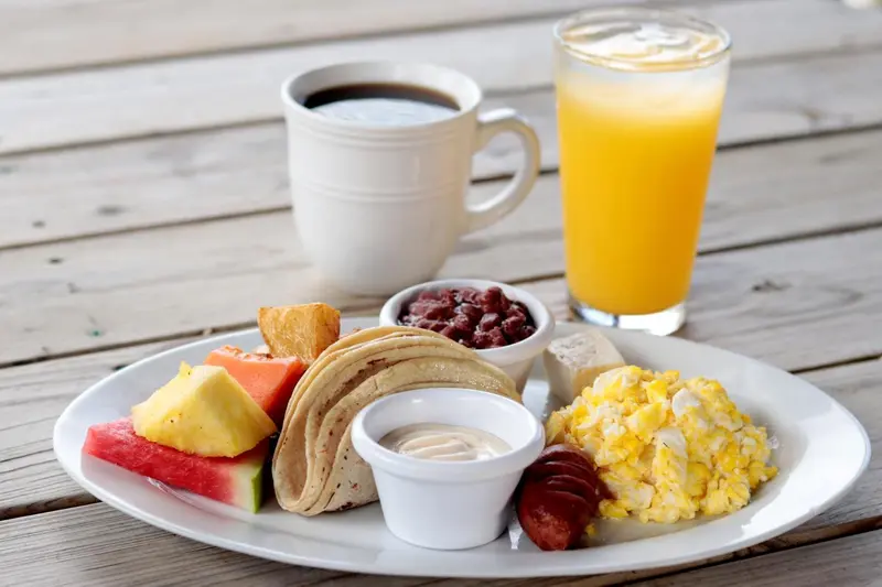 Un petit-déjeuner copieux est présenté sur une assiette blanche et un plateau en bois.