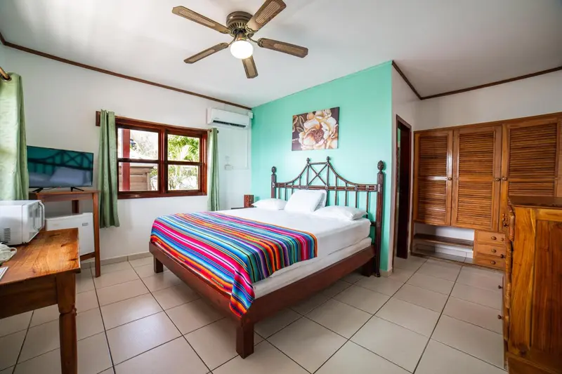 Une chambre lumineuse avec un grand lit recouvert d'une courtepointe colorée.