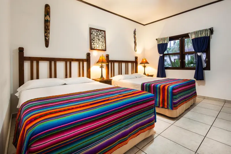 Une chambre lumineuse avec deux lits recouverts de couvertures colorées.