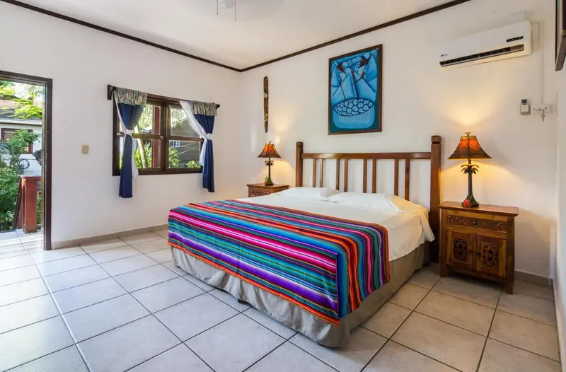 Une chambre lumineuse avec un grand lit recouvert d'une courtepointe colorée.