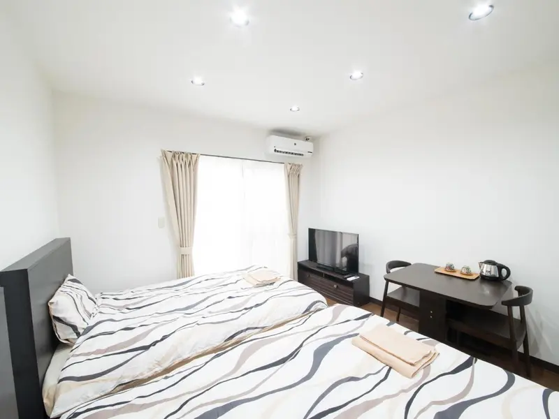 Une chambre lumineuse avec un lit fait et un coin repas.