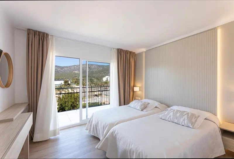 Chambre lumineuse avec vue sur un paysage montagneux.