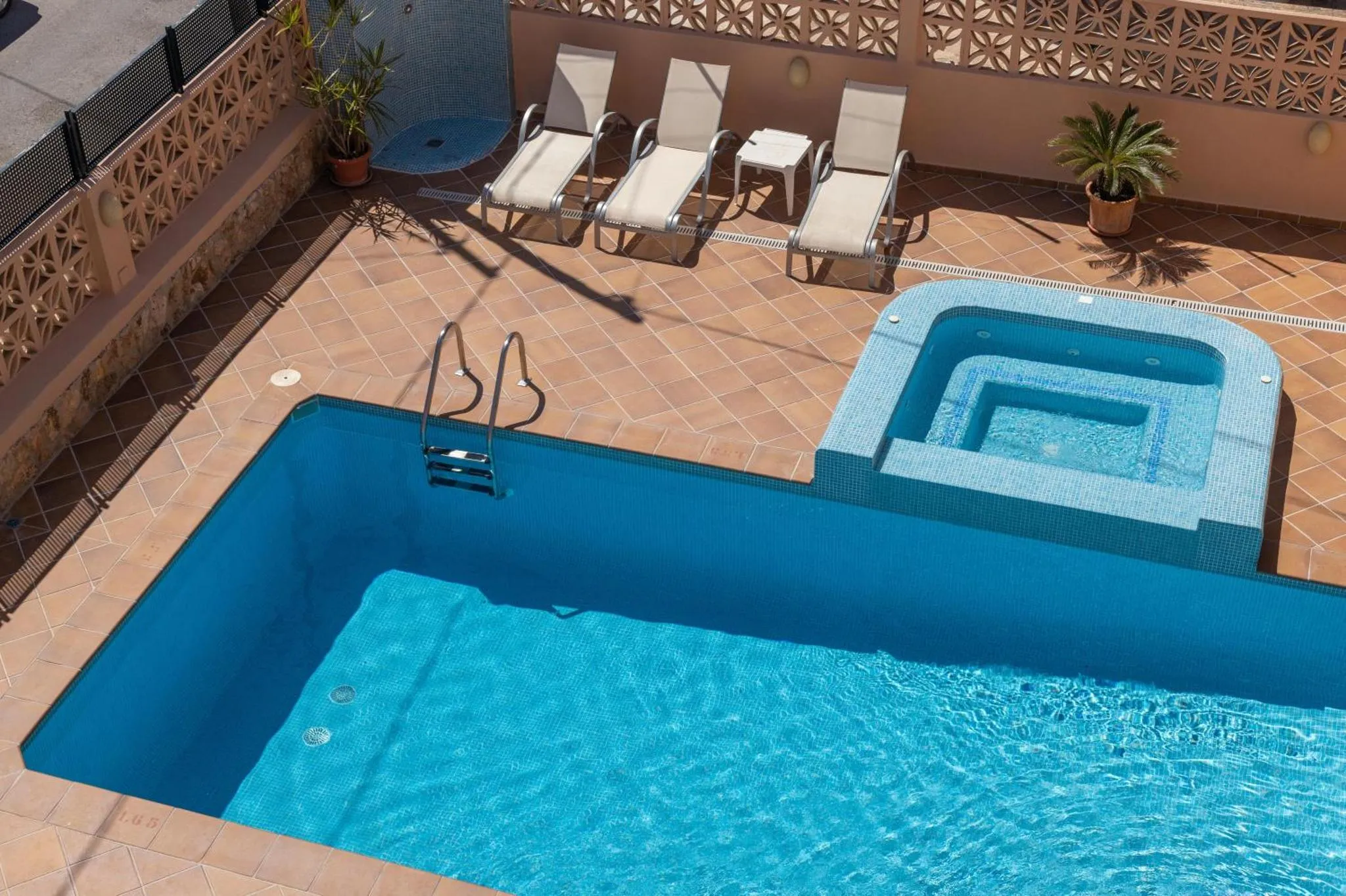 Terrasse avec piscine et chaises longues à l'ombre.