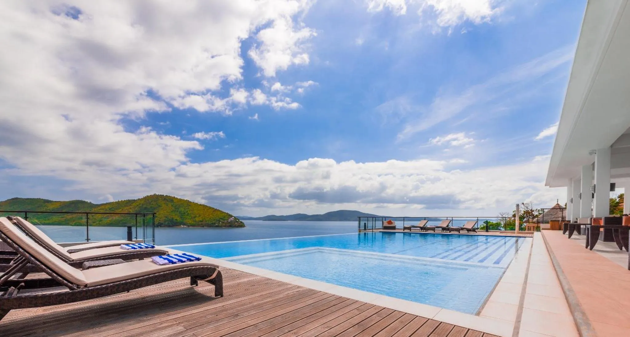 Transats alignés au bord d'une piscine à débordement avec vue sur la mer.