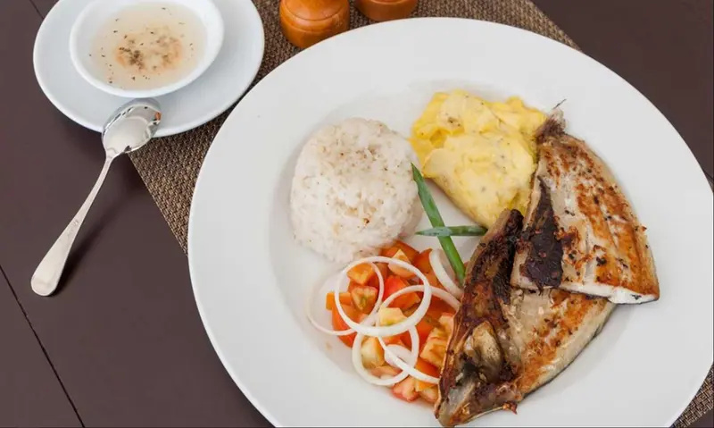 Assiette de riz, poisson grillé, œuf brouillé et légumes.