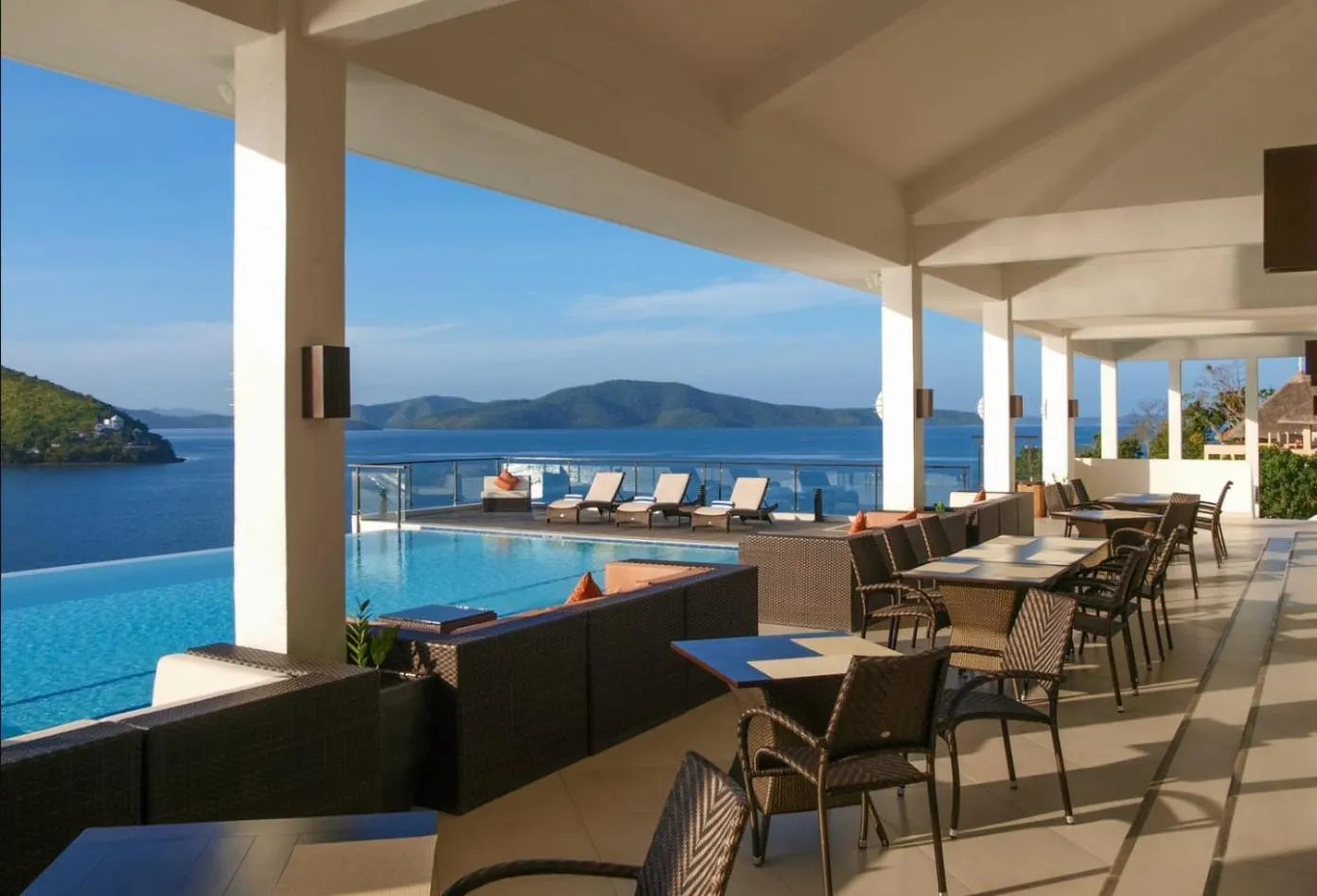 Terrasse avec mobilier de détente et piscine à débordement donnant sur la mer.